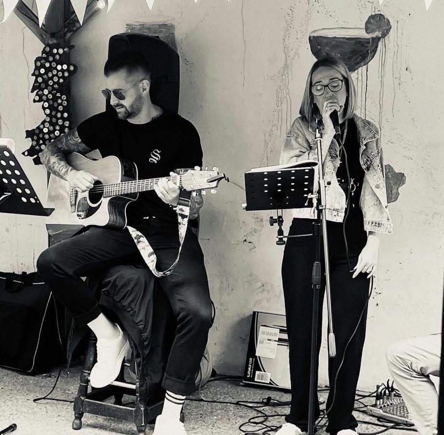 DS on guitar and Vix singing in a courtyard